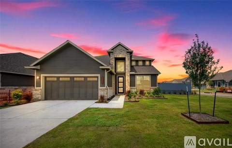 A house with a garage and a tree in front of it.