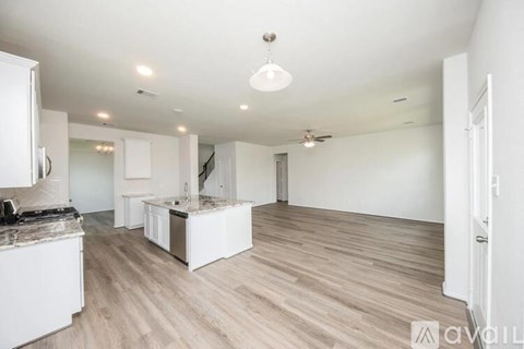 A spacious kitchen with white cabinets and a wooden floor.