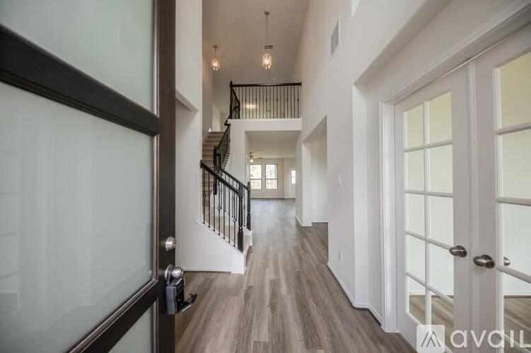 A hallway with a staircase and a glass door.