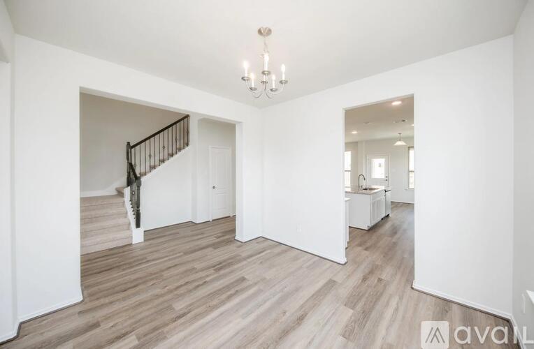 A spacious room with wooden flooring and a chandelier.