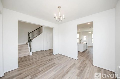 A spacious room with wooden flooring and a chandelier.
