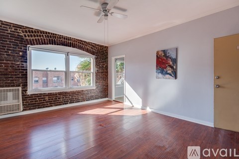 A room with a brick wall and wooden flooring is available for rent.
