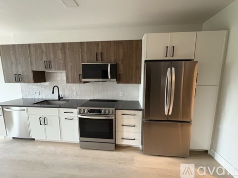 A kitchen with a stainless steel refrigerator and a black countertop.