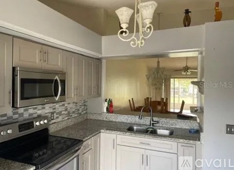 A kitchen with a black stove top oven and a black microwave above a double sink.