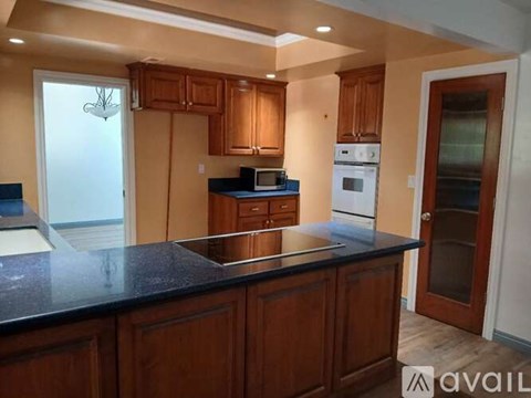 A kitchen with wooden cabinets and a black countertop.
