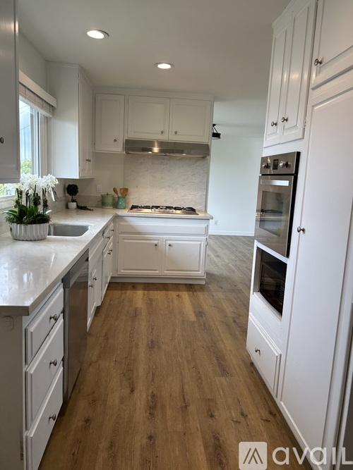 A kitchen with white cabinets and a wooden floor.