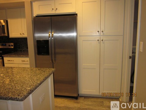 A stainless steel refrigerator in a kitchen with granite countertops.