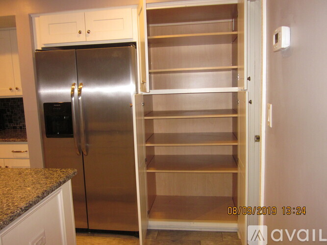 A stainless steel refrigerator with its door open in a kitchen.