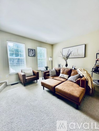 A living room with a brown couch and a white chair.