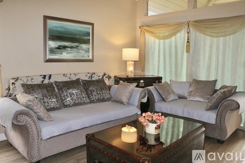 A living room with a grey sofa, a coffee table, and a painting on the wall.