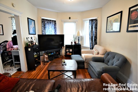 A living room with a brown leather couch and a television.
