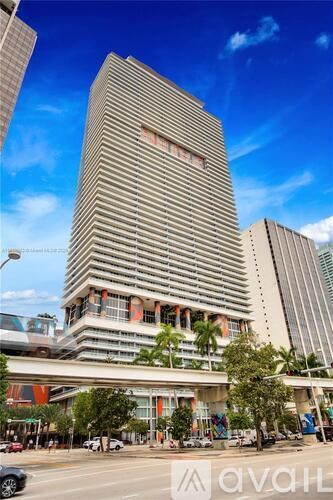 A tall building with a striped facade stands in the middle of a city street.