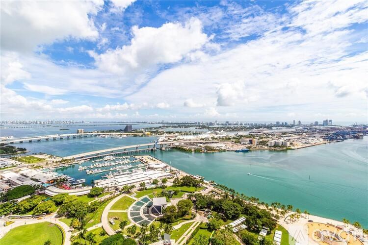 A large body of water with a bridge in the background and a circular building in the foreground.