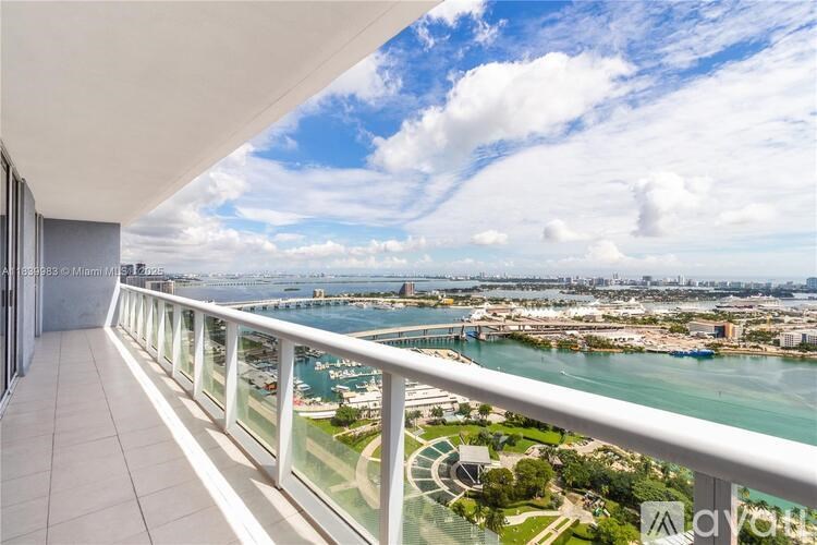 A balcony overlooks a cityscape with a body of water and boats.