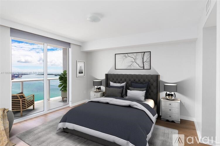 A bedroom with a large bed and a view of the ocean through the sliding glass doors.