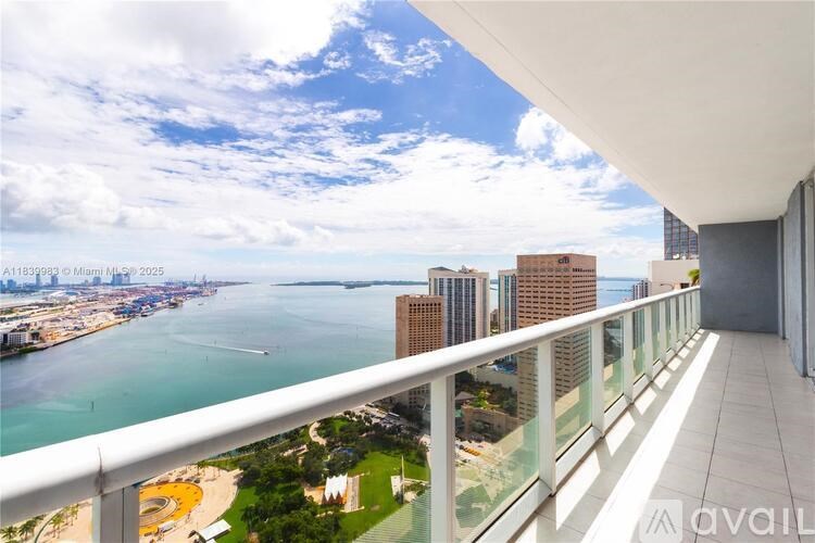 A balcony overlooks a cityscape with a body of water and a clear sky.