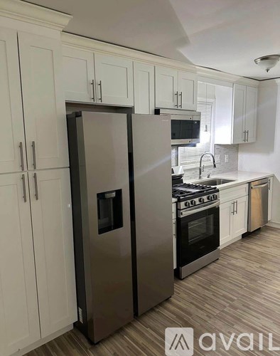 A kitchen with a stainless steel refrigerator and white cabinets.