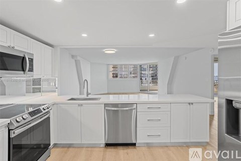 A modern kitchen with white cabinets and stainless steel appliances.