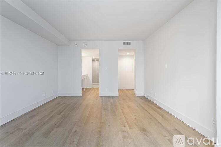 A spacious room with wooden flooring and white walls.
