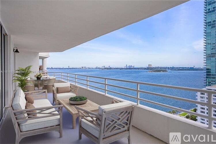 A balcony with chairs and a table overlooking a body of water.