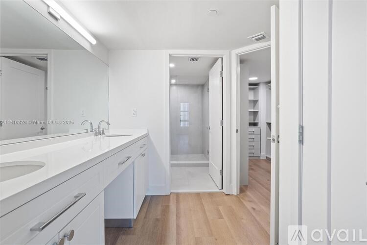 A bathroom with a white vanity and a walk-in shower.