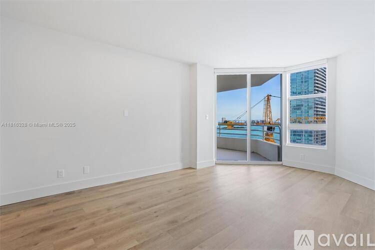 A room with wooden flooring and a view of a bridge through the window.