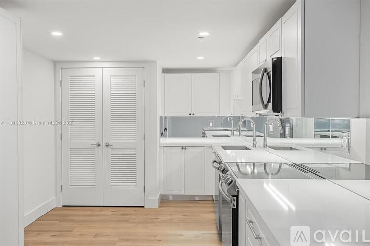A modern kitchen with white cabinets and a wooden floor.