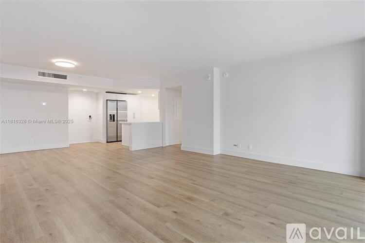 A spacious room with wooden flooring and white walls.