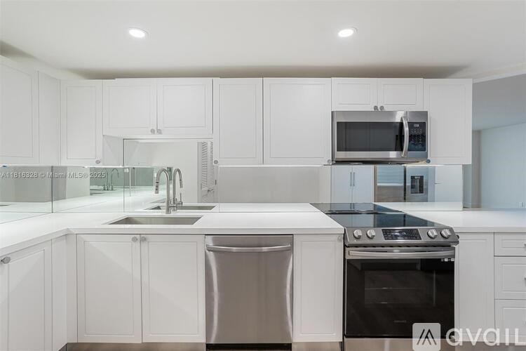 A modern kitchen with white cabinets and stainless steel appliances.
