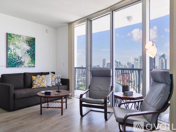 A living room with a couch, two chairs, and a table with a book on it.