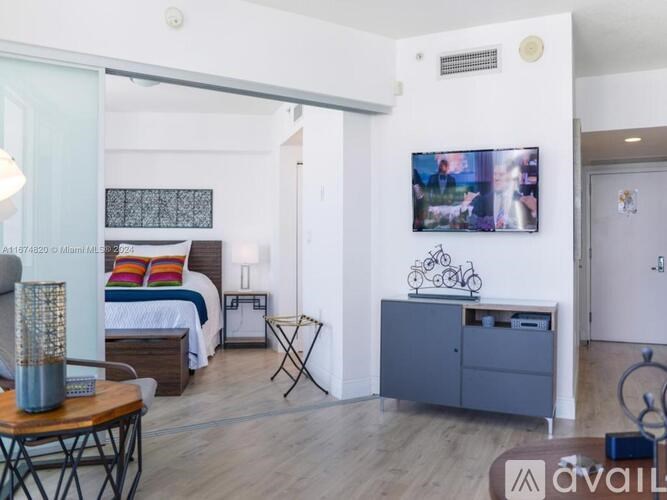A modern bedroom with a large bed and a flat screen TV mounted on the wall.