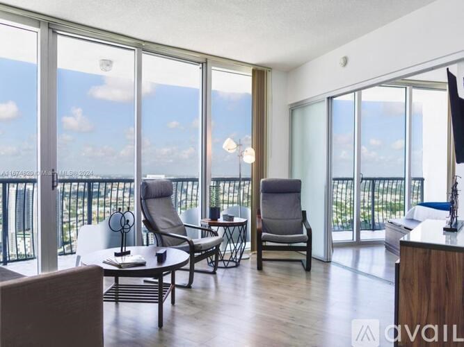A living room with a balcony overlooking the outdoors.