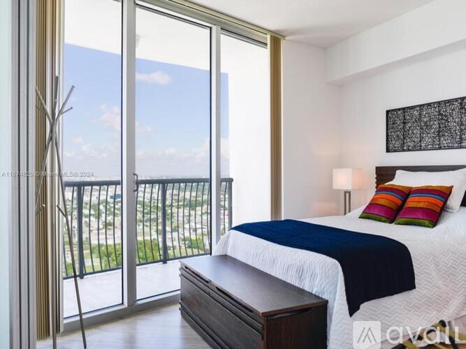 A bedroom with a large bed and a balcony with a view of the outside.