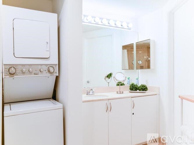 A white bathroom with a washing machine and a mirror.