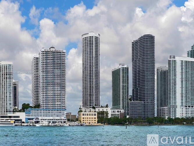A cityscape with tall buildings and a body of water in the foreground.