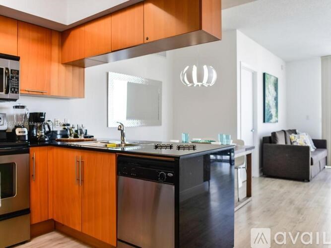 A modern kitchen with orange cabinets and stainless steel appliances.