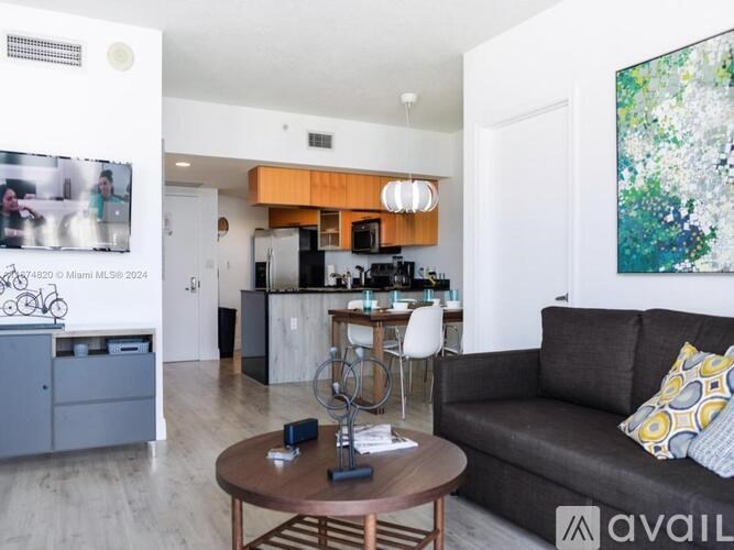 A living room with a couch, a coffee table, and a kitchen area in the background.