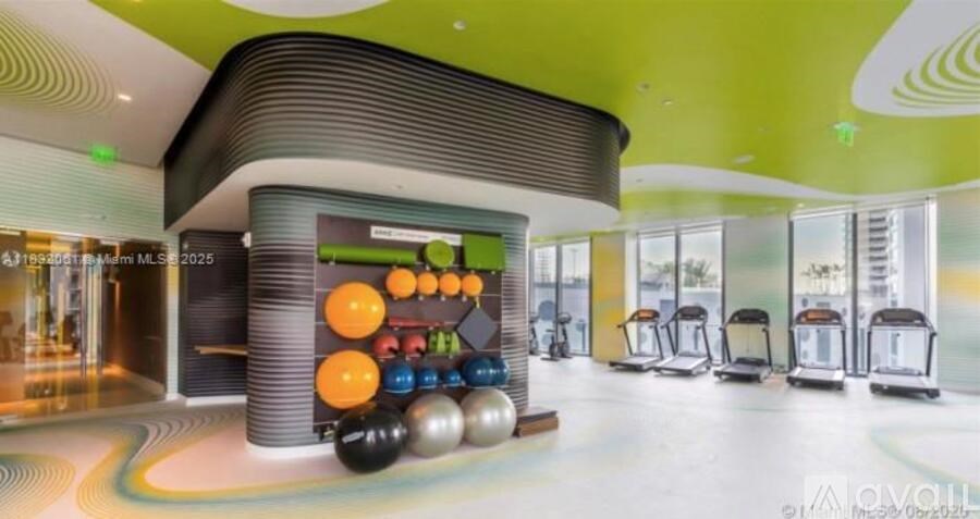 A bowling alley with a green wall and a row of chairs.