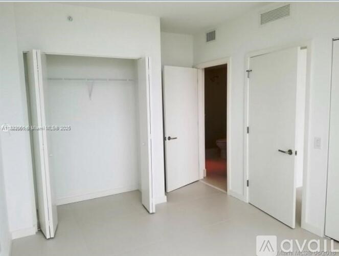 A white room with a door and a wall-mounted shelf.