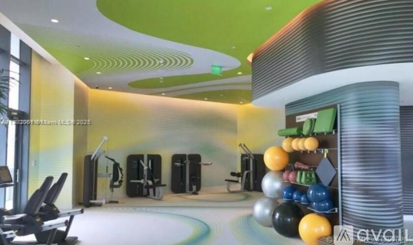 A gym with a variety of equipment including treadmills, weights and exercise balls.