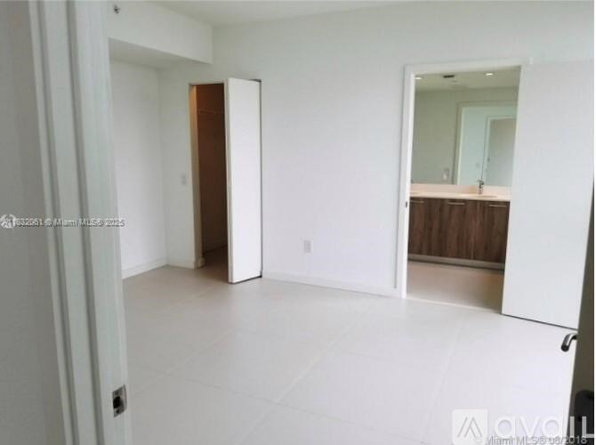 A white room with a door and a mirror on the wall.