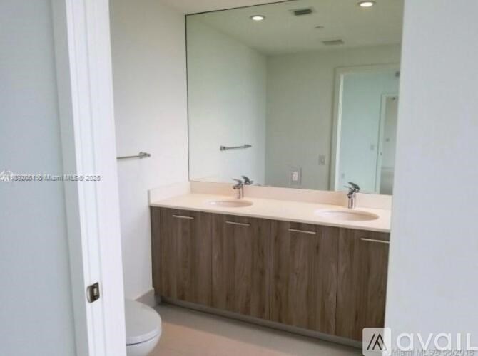 A bathroom with a white toilet and a vanity with a sink and mirror.