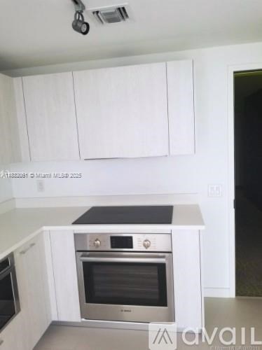 A kitchen with white cabinets and a stainless steel oven.