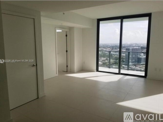 A spacious room with a view of the cityscape through large windows.