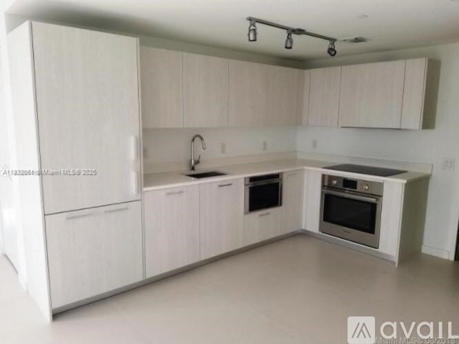 A kitchen with white cabinets and appliances is available for rent.