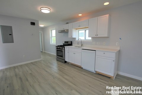 A kitchen with white cabinets and a wooden floor.