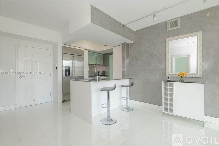 A modern kitchen with a bar area and a fridge in the background.