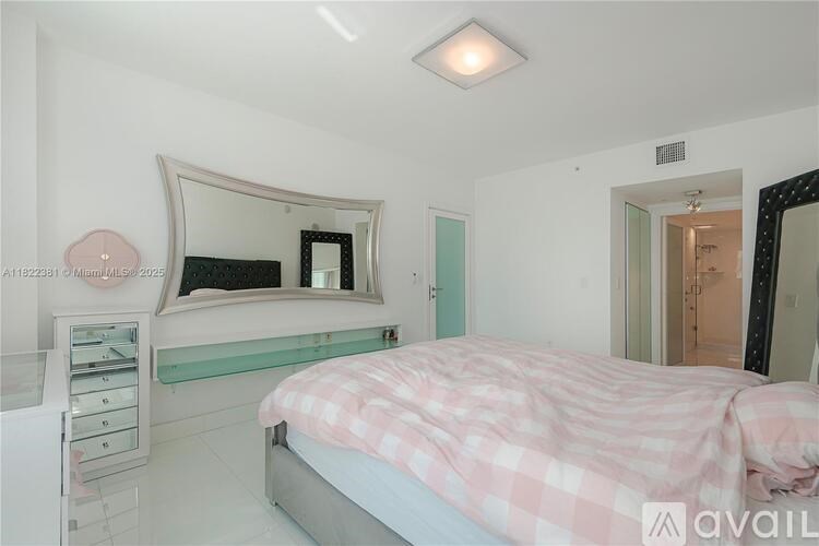 A bedroom with a pink bedspread and a large mirror above the bed.