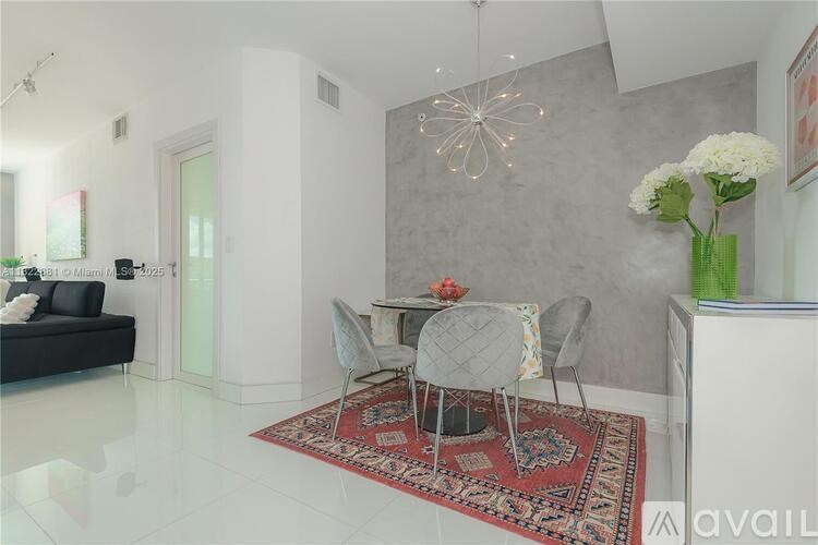 A dining room with a table set for two and a rug on the floor.