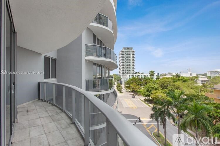 A balcony overlooks a street with palm trees and buildings.